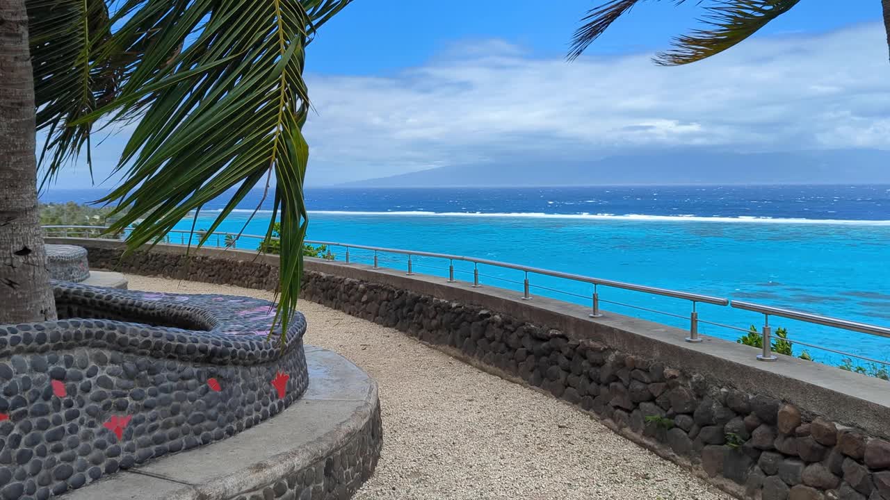Scenic tourism lookout on tropical island of Moorea, French Polynesia overlooking crystal clear blue ocean water on windy day