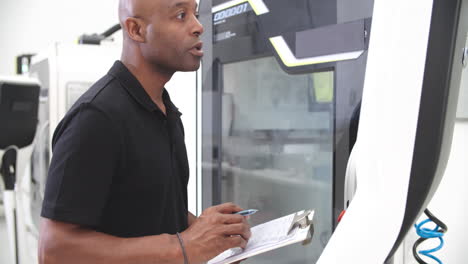 male engineer operating cnc machinery on factory floor