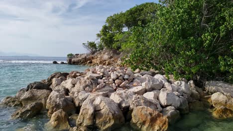 cerrar la vista de ángulo bajo del agua clara del caribe que se lava contra la costa rocosa de una pequeña isla tropical