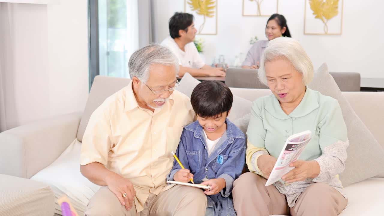 Elderly couple assists young boy with writing, sharing laughter in sunlit, modern family living room