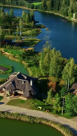 An aerial drone view of stunning and unique eco-village of Amatciems in Latvia, where beautiful houses with natural roofs are seamlessly integrated into a landscape of pristine lakes and forests