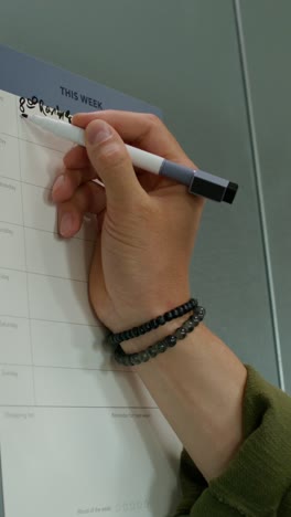 person writing on a weekly planner