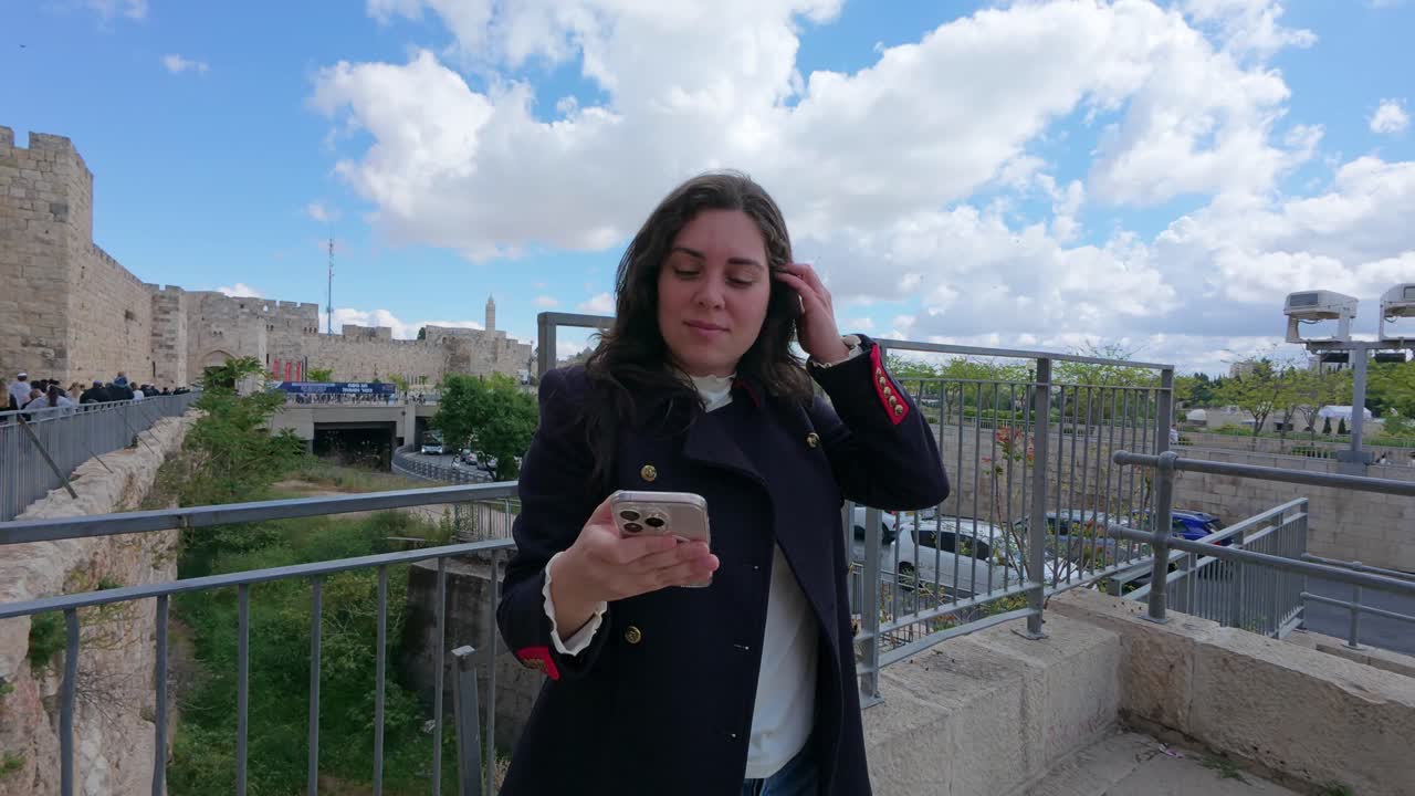 Turista che scrive messaggi sul cellulare presso un punto di riferimento storico a Gerusalemme. Al rallentatore.