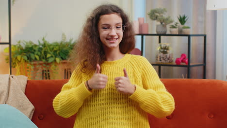 niña feliz niña mirando con aprobación a la cámara mostrando los pulgares hacia arriba, como un signo positivo, buenas noticias