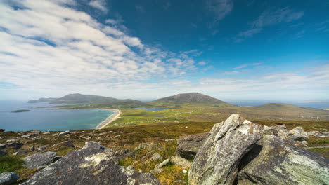 Timelapse-of-seaside-remote-bogland-village-with-sand-beach,-grass-and-rocks-with-clouds-casting-shadows-on-sunny-day-viewed-from-Minaugn-Heights-in-Achill-Island-in-county-Mayo-in-Ireland