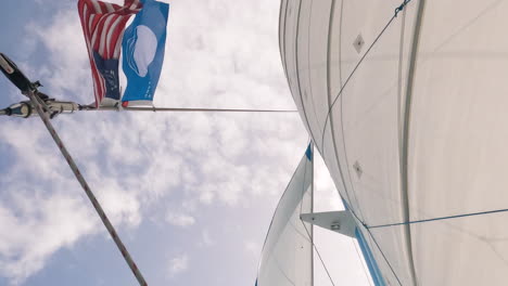 low angle shot of saiboat sails and mast with flags blown by wind, day