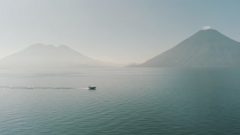 drone aerial, boat driving over lake atitlan during the morning in guatemala