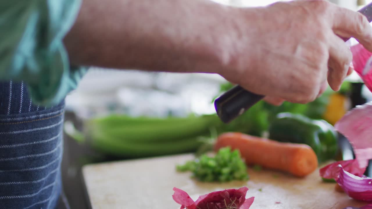 primer plano de las manos del hombre cortando cebolla roja en una tabla de cortar
