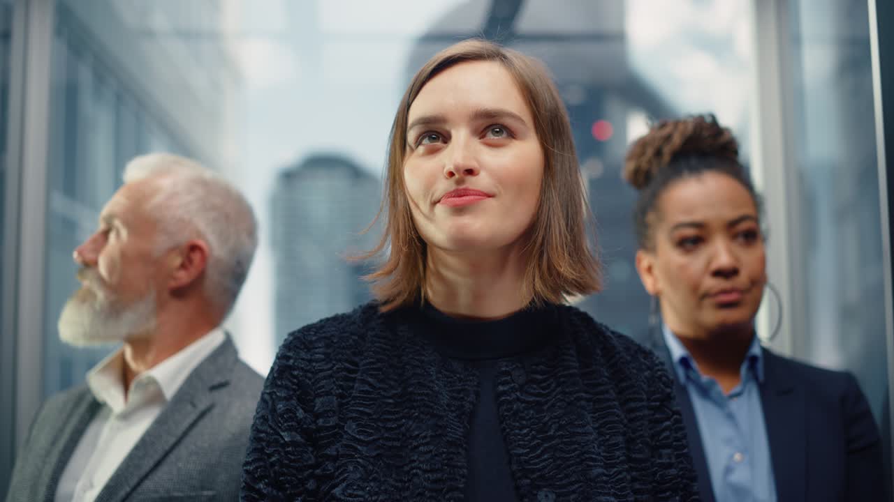 Three Diverse Multiethnic International People Ride a Glass Elevator to Office in a Modern Business Center. Focus on Different Businesspeople Standing in a Lift.