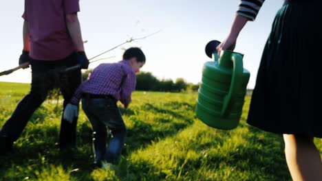 the farmer's family together is going to plant a tree. back view, in the foreground of watering can. steadicam shot