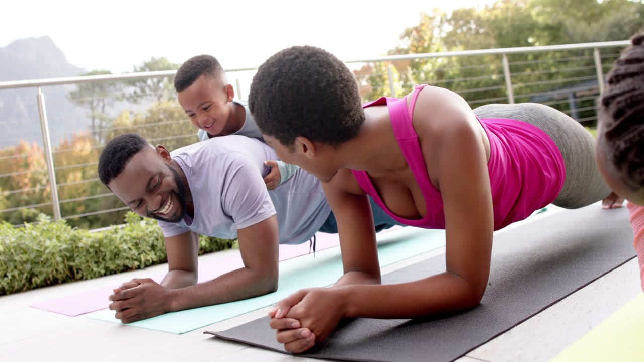 felices padres afroamericanos, hijo e hija practicando yoga en un jardín soleado, en cámara lenta.