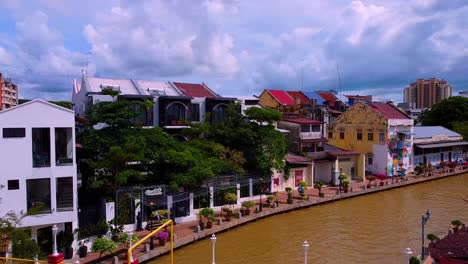 Vuelo-Aéreo-Sobre-El-Río-Melaka-Con-Coloridos-Puentes-Y-Edificios-De-Casas,-Asia