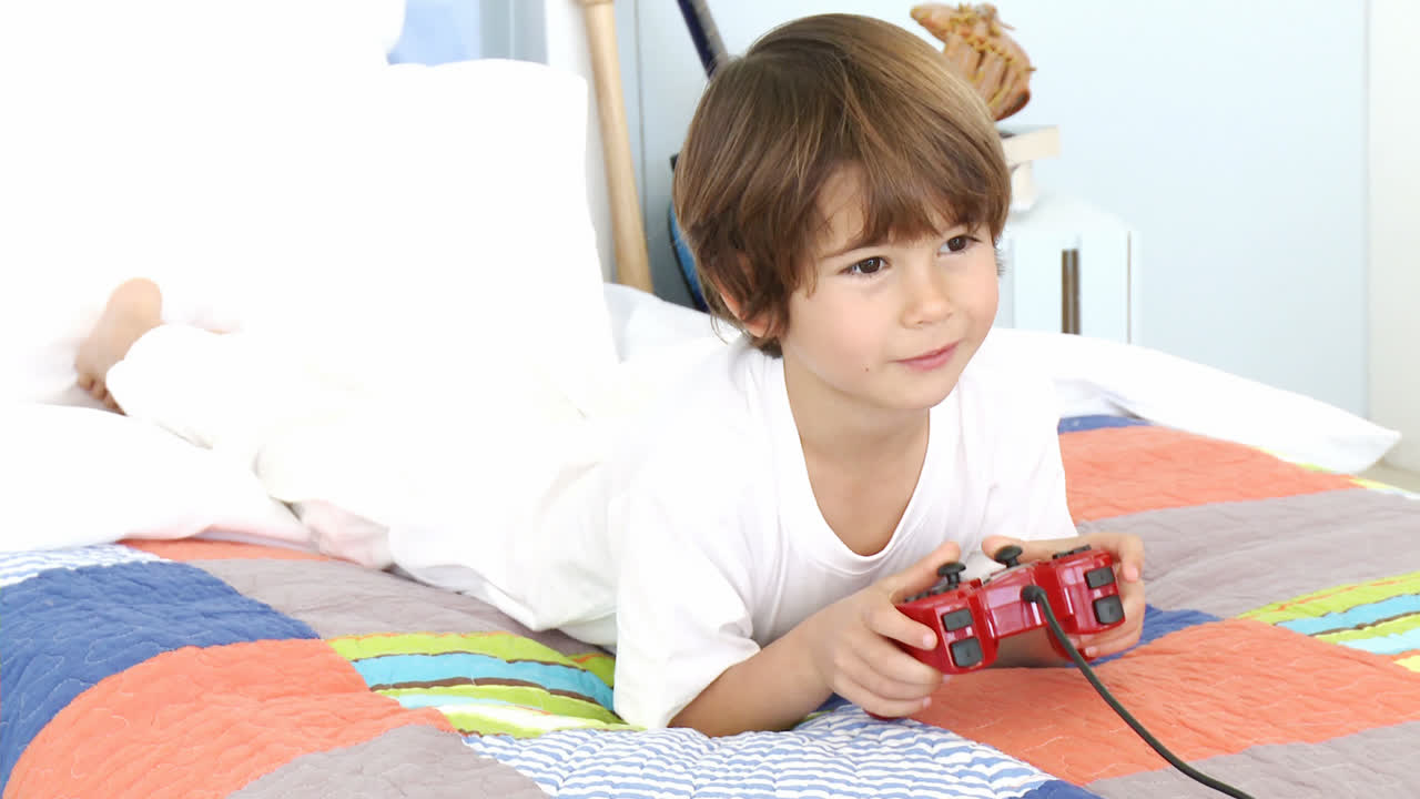 Bambino che gioca ai videogiochi sul letto