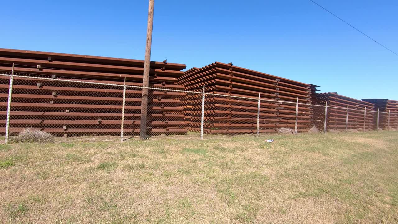 pov pasando por paneles metálicos almacenados para construir el muro fronterizo entre texas, ee.uu. y méxico