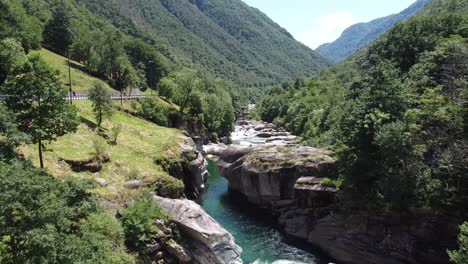 Aerial-backwards-shot-over-Beautiful-river-in-Switzerland-surrounded-by-green-mountains-in-summer