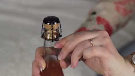 female hands opening bubbly wine celebrating party, static closeup