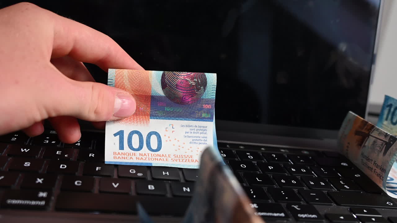 un usuario de dispositivo electrónico que hizo un negocio en línea muestra billetes de banco sobre el teclado de su computadora portátil