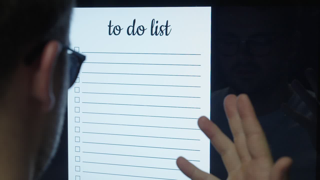 A man looks at a digital to-do list displayed on a screen — concept of productivity, organization, planning, and digital workflow