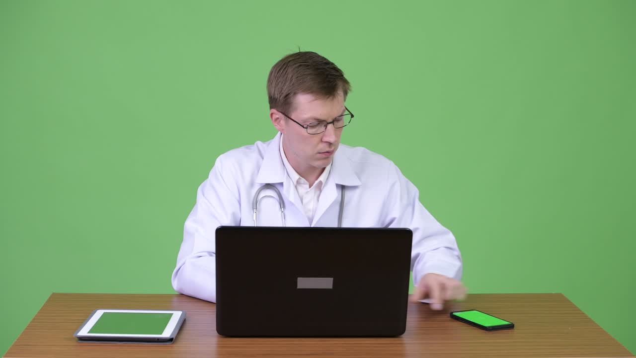 Portrait Of Young Man Doctor Sitting And Using Laptop Computer