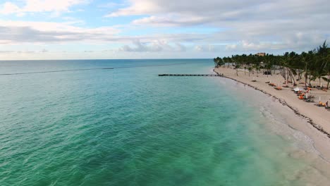 Serene-tropical-beach-with-people,-unrecognizable-on-sunchairs-at-sunset,-sunrise,-serenity-and-getaway-vacation-in-Caribbean-sea,-Dominican-Republic-travel-destination