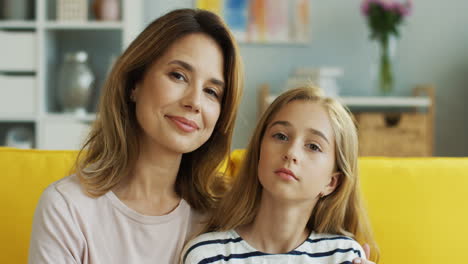 retrato de madre e hija sentadas en un sofá amarillo