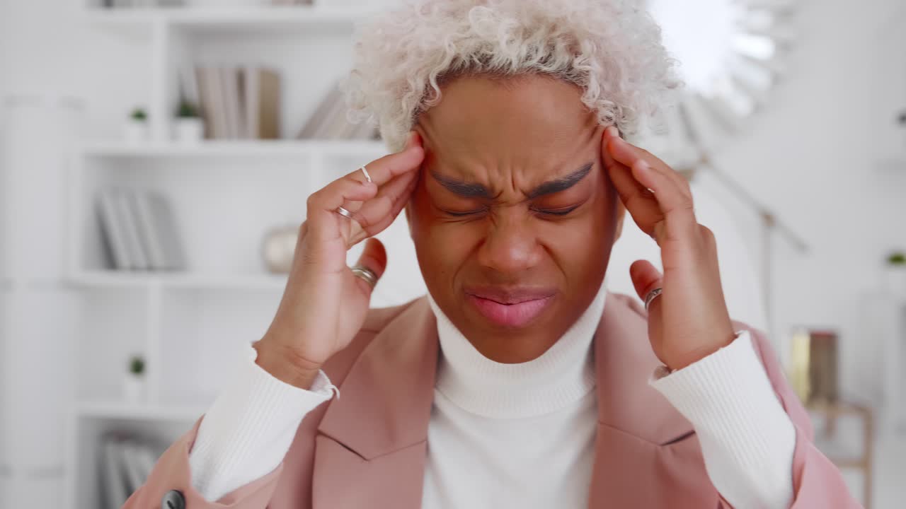 joven mujer de negocios afroamericana que sufre de dolores de cabeza