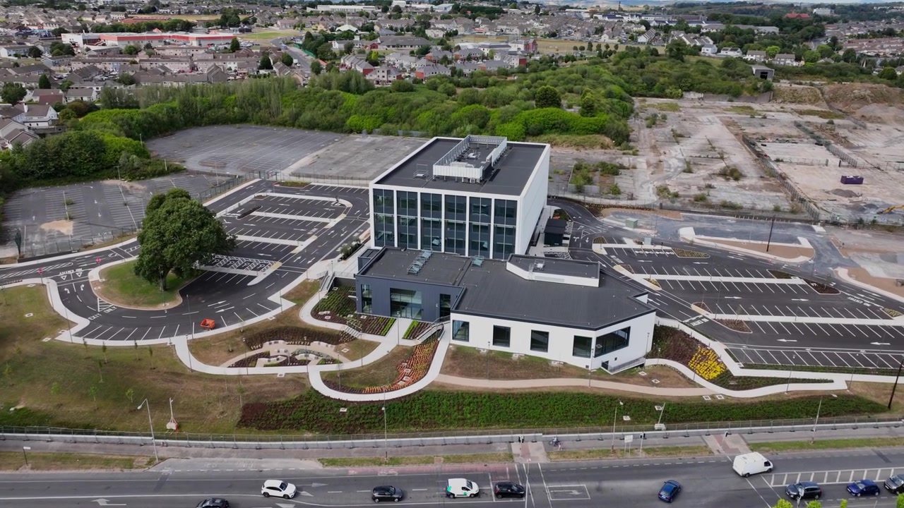 Højopløselig droneoptagelse, der nærmer sig New Glassworks Centre, som afslører dets moderne arkitektur og placering i Waterfords voksende erhvervsmiljø. Ideel etableringsoptagelse.