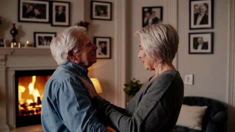 happy senior couple dancing by the fireplace