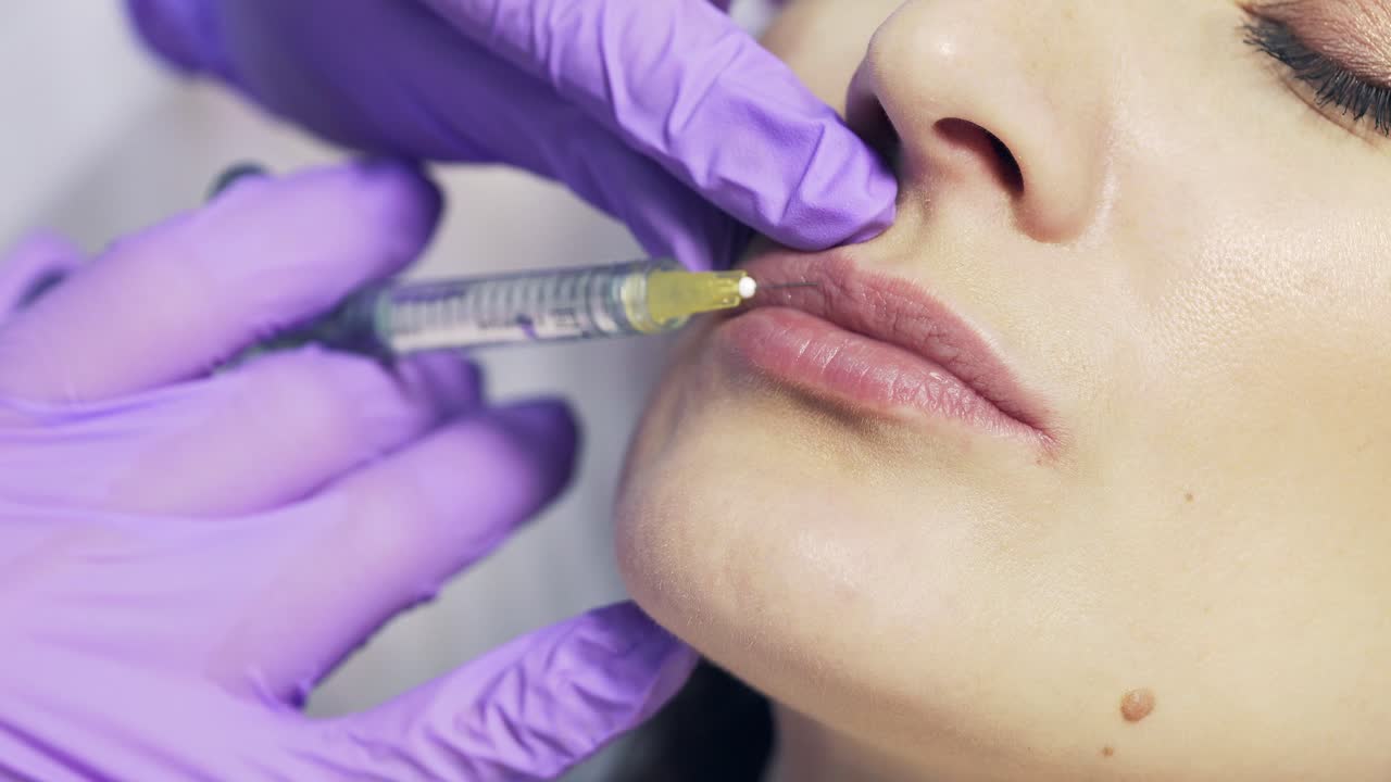 Woman receiving injections in lips zone in clinic. Hands of doctor making injection in female lips.Cosmetology concept