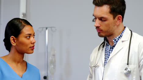 Nurse-and-doctor-discussing-over-clipboard