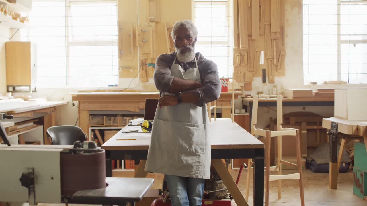 Portrait of african american male carpenter with arms crossed smiling in a carpentry shop