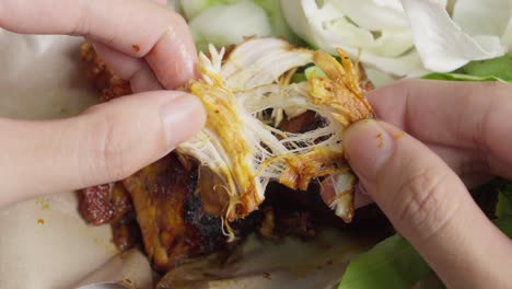 closeup of hands peeling ayam bakar indonesian grilled chicken with cabbage