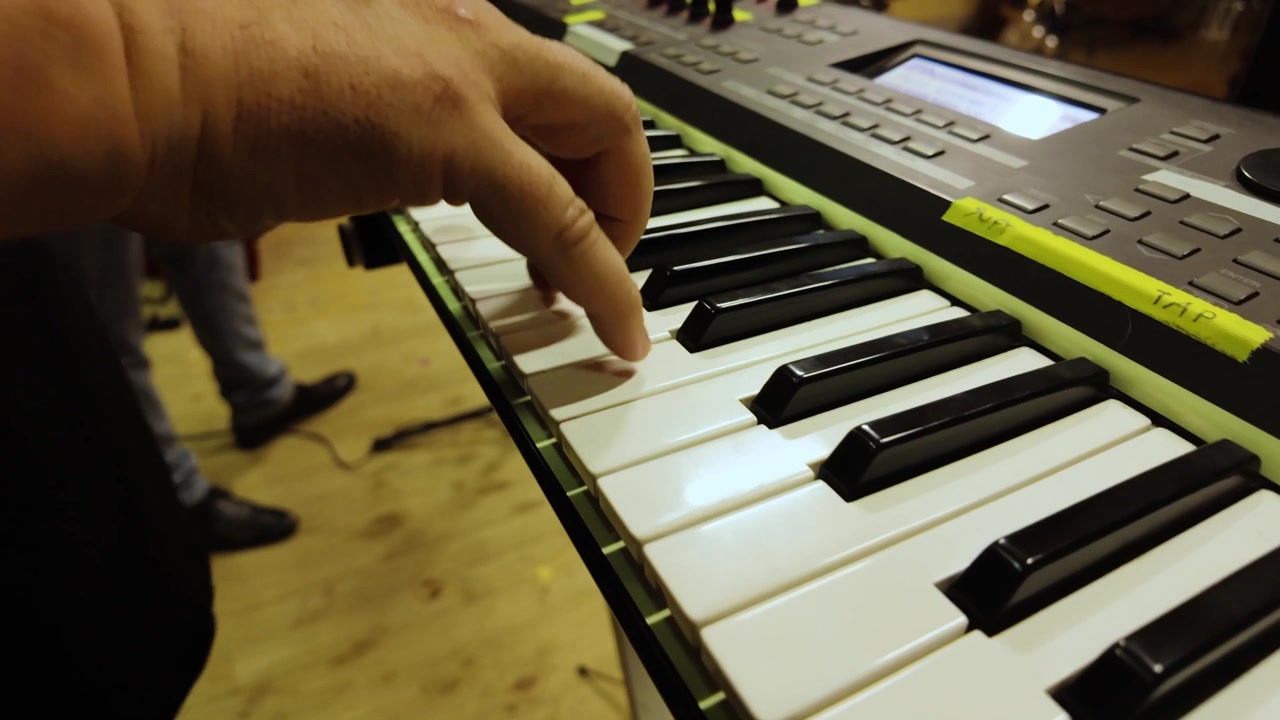 Musicista che suona una tastiera elettronica in una performance drammatica al rallentatore.