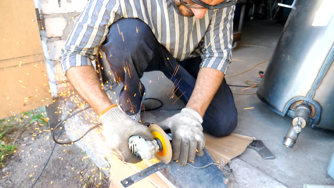 Adult repairman or mechanic grinding metal using circular saw. Worker cutting some detail in garage. Man sawing iron part with electric grinding wheel. Slow motion Close up