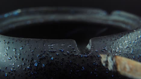 a macro close up shot of ash residue from a cigarette in a black stone ashtray, slow motion 4k video, white smoke