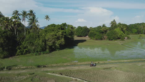 Shot-of-A-person-riding-a-motorcycle-on-a-farm-road-in-Langkawi-Island,-Malaysia