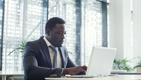 african businessman typing on laptop in coworking space