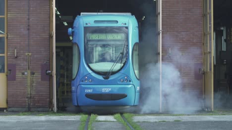 a recently serviced bright blue tram exits the main maintenance garage in downtown zagreb, croatia