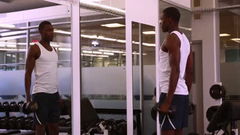 fit man lifting dumbbells looking in mirror