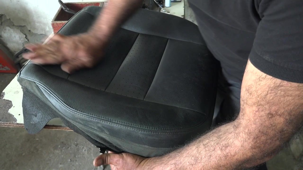 Mecánico instalando una nueva funda de cuero en un asiento de coche