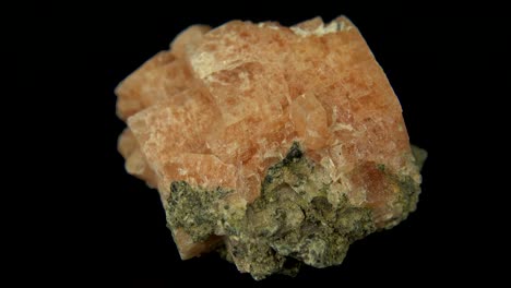 검은색 배경 앞에 분홍색 광물 (chabazite-ca) 을 원활하게 회전시니다.