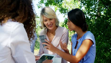 female friends discussing over mobile phone at outdoor cafã©