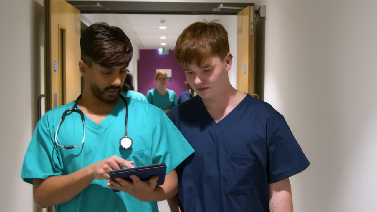 Medical Staff Using Tablet Walking In Corridor