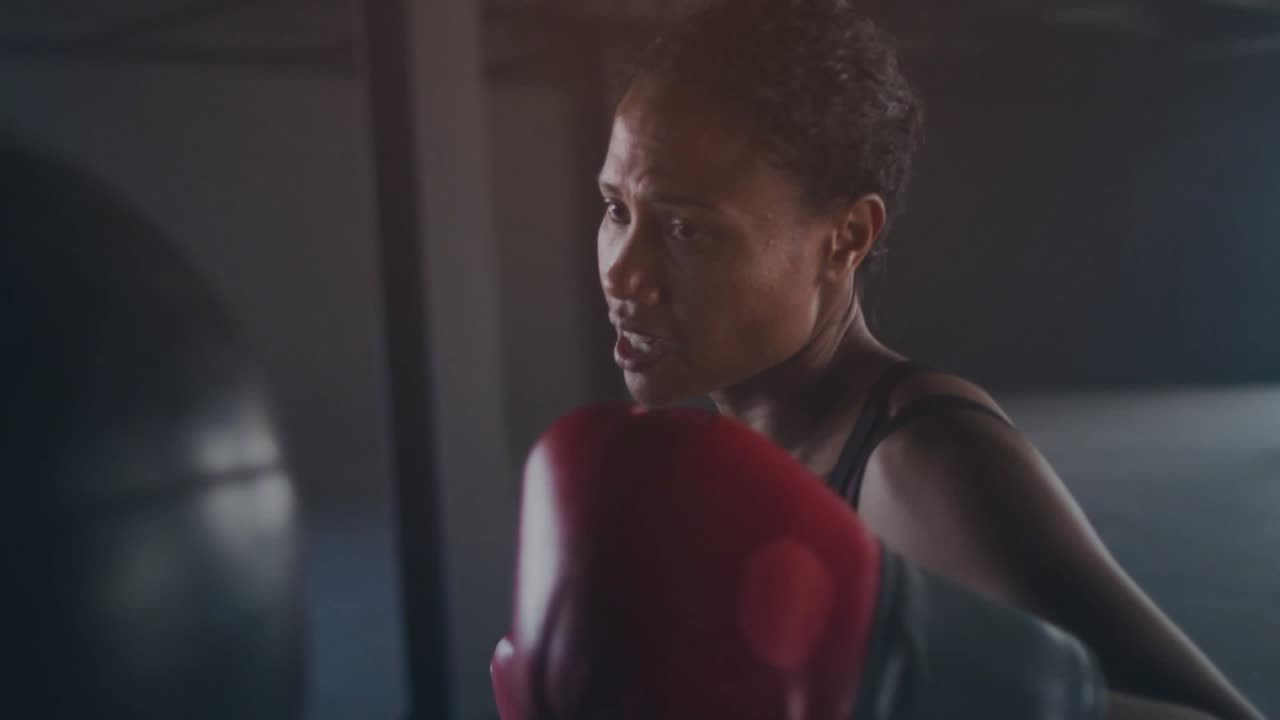 Boxer donna che alza dei guantoni rossi in palestra, HUD in sovrapposizione che guida i jab per parametri di addestramento