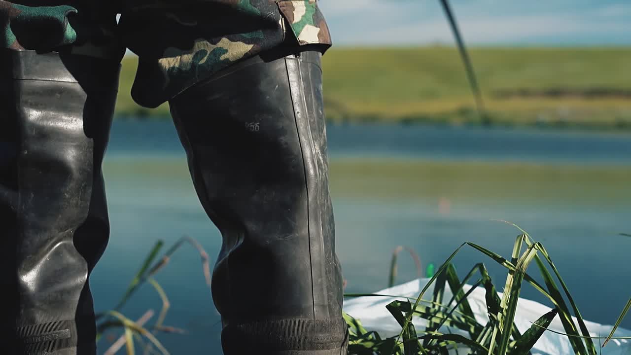 fisherman stands in boots and catches fish