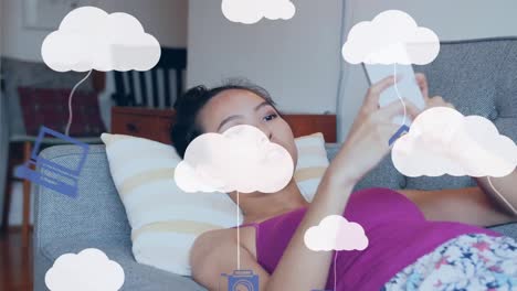 Animation-Von-Wolken-Und-Digitalen-Symbolen-über-Einer-Frau,-Die-Ihr-Smartphone-Nutzt