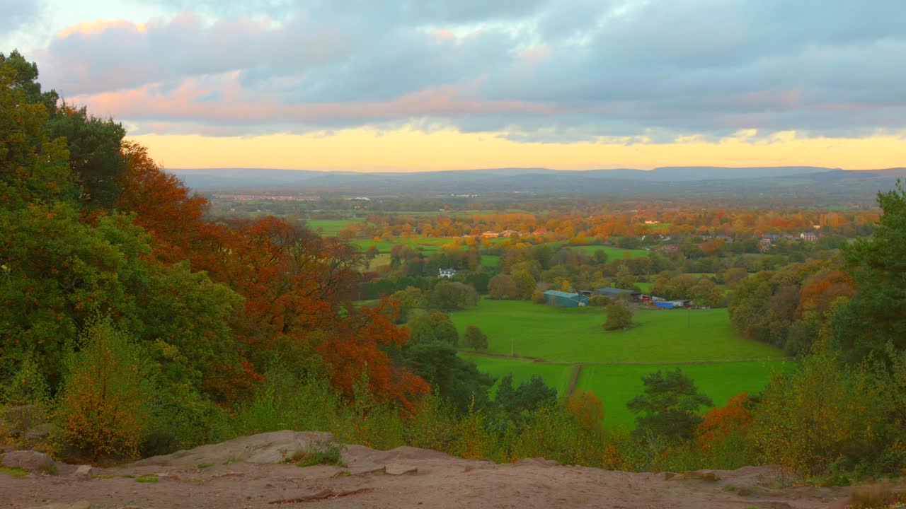 Gli alberi autunnali colorati, i campi verdi della pianura del Cheshire e l'orizzonte dorato in Inghilterra