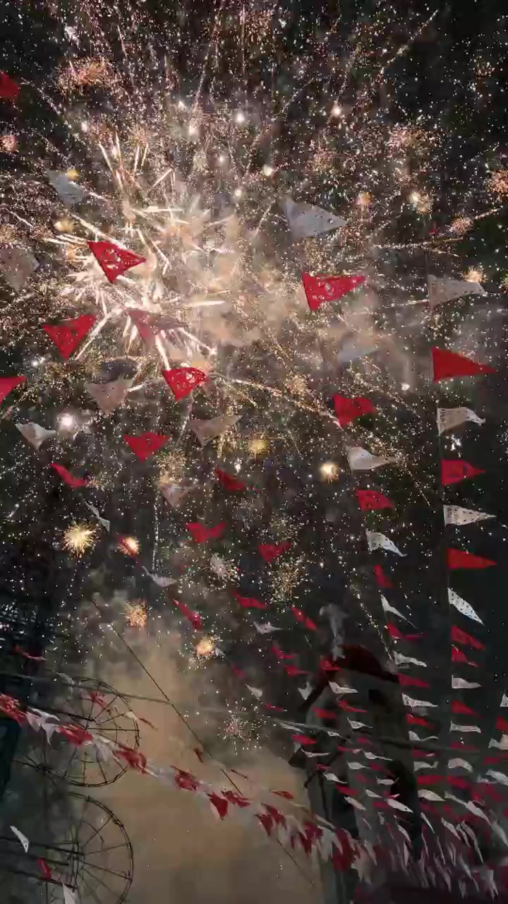Fuochi d'artificio colorati che illuminano il cielo notturno durante una celebrazione tradizionale con bandiere, Messico.