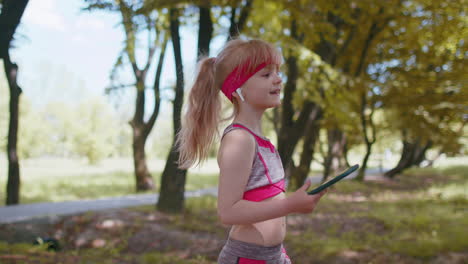 atletismo, fitness, deporte, corredor, niño, niña, caminando, usando un teléfono inteligente, escuchando música con auriculares