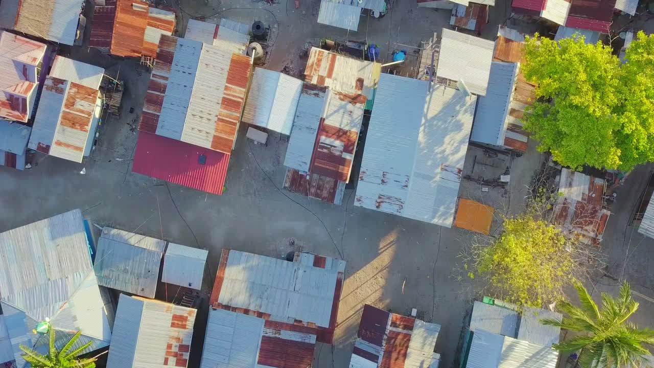 vuelo aéreo sobre cabañas y casas en sunny beach village en mabul, malasia